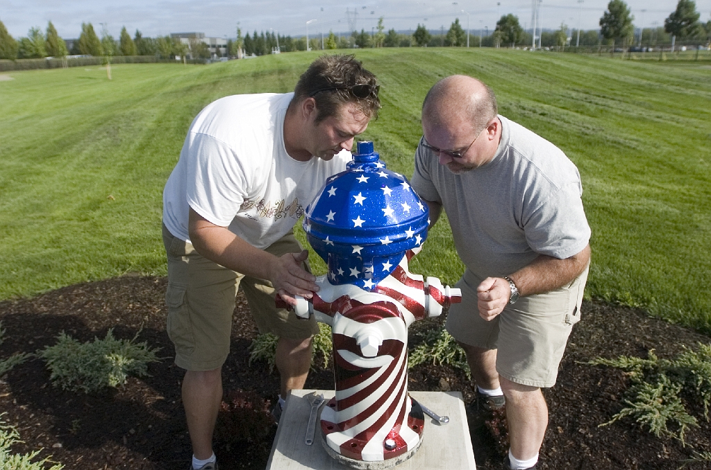 blog.oregonlive.com-washingtoncounty-hondoWed.JPG - Jason Ross (CQ), left, the artist who decorated the pictured fire-hydrant that is dedicated to Hondo, the Hillsboro Police Dog that was killed in the line of duty, attaches the hydrant to it's pedestal Friday, Sept. 7, 2007 with Hillsboro Dog Park Association co-chair Mike Chapman (CQ), right, who decorated another hydrant in the park with cartoon dogs. The new Hillsboro dog park will be opening soon, joining a growing popularity for dog parks in the region. Hillsboro's park, in particular, has many doggie amenities, such as a special place for small and timid dogs to play and a winter play area. Photo by Olivia Bucks/The Oregonian  Olivia cell: 503.957.1355